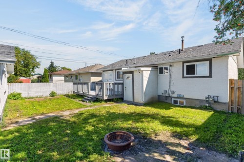 Spacious backyard with a grey wood deck, white vinyl fencing, and a separate side entrance - 13214 123 Street Nw, Edmonton, AB 