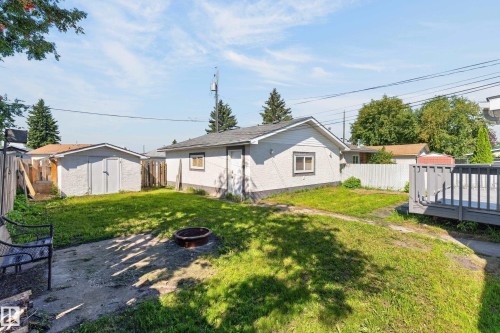 Expansive backyard featuring a manicured lawn, a detached building with stucco siding, and a wooden deck - 13214 123 Street Nw, Edmonton, AB 