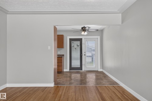 Wood-finish flooring, light gray wall tones, crown molding, double glass-paneled doors, and a ceiling fan - 13214 123 Street Nw, Edmonton, AB 