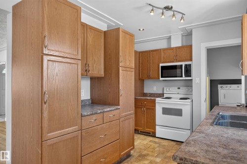 Kitchen featuring wood-finish cabinetry, laminate countertops, and stainless steel sink - 13214 123 Street Nw, Edmonton, AB 