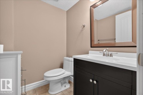 Powder room featuring a dark wood-finish vanity with a white countertop, chrome faucet, and a large framed mirror - #47 3812 20 Av Nw, Edmonton, AB 