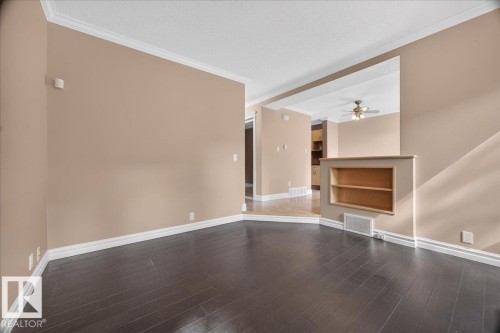 Dark wood-finish flooring with white trim, recessed built-in shelving, and a dropped ceiling with crown molding - #47 3812 20 Av Nw, Edmonton, AB 