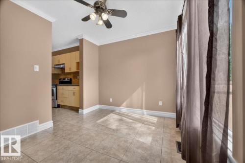 Tiled flooring, crown molding, ceiling fan, and a kitchen featuring wood-finish cabinetry and stainless steel appliances - #47 3812 20 Av Nw, Edmonton, AB 