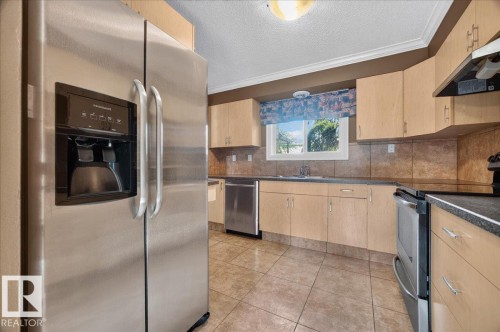 Stainless steel side-by-side refrigerator, tile flooring, light wood-finish cabinetry, built-in stainless steel dishwasher, and built-in stainless steel range - #47 3812 20 Av Nw, Edmonton, AB 