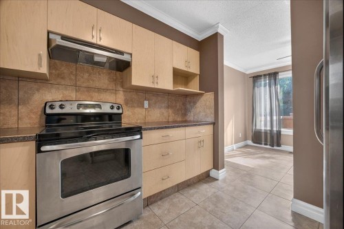 Stainless steel range, wood-finish cabinetry, tile backsplash, laminate countertops, and tile flooring - #47 3812 20 Av Nw, Edmonton, AB 