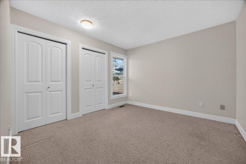 Neutral-toned carpeting, light wall paint, dual white bi-fold closet doors, and natural light from a rectangular window - #47 3812 20 Av Nw, Edmonton, AB 