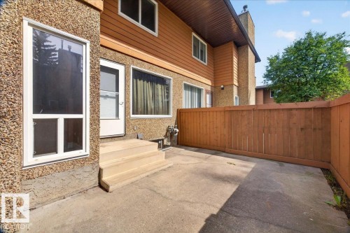 Private concrete patio featuring a wood privacy fence and exterior entry - #47 3812 20 Av Nw, Edmonton, AB 