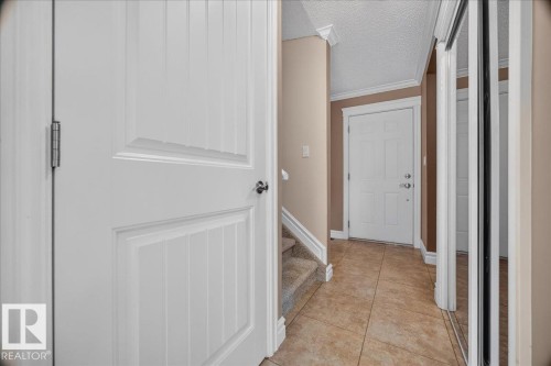 Foyer featuring tiled flooring, white paneled doors, and a mirrored closet - #47 3812 20 Av Nw, Edmonton, AB 