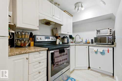 White cabinetry with brushed nickel hardware, stainless steel range, and light-toned countertops - 9740 63 Avenue Nw, Edmonton, AB 