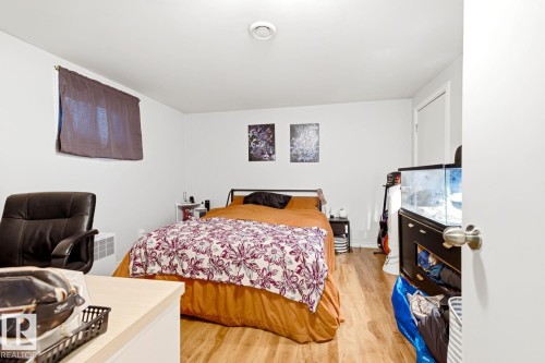 Basement Bedroom - Spacious bedroom featuring wood-finish flooring, ample natural light from multiple windows, and generous floor space accommodating a full bed and additional furnishings - 9740 63 Avenue Nw, Edmonton, AB 