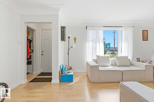 Bright, open living area featuring warm wood-finish flooring, expansive windows with natural light, and a neutral color palette - 9740 63 Avenue Nw, Edmonton, AB 