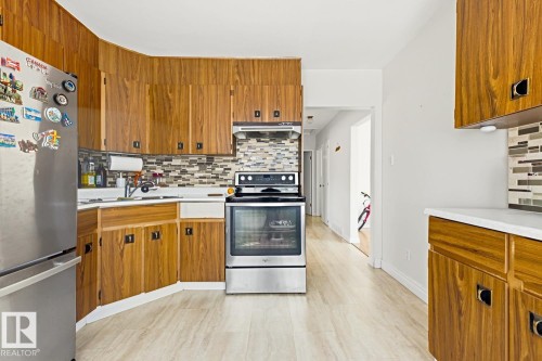 Wood-finish cabinetry, stainless steel range, and light wood-finish flooring - 9740 63 Avenue Nw, Edmonton, AB 