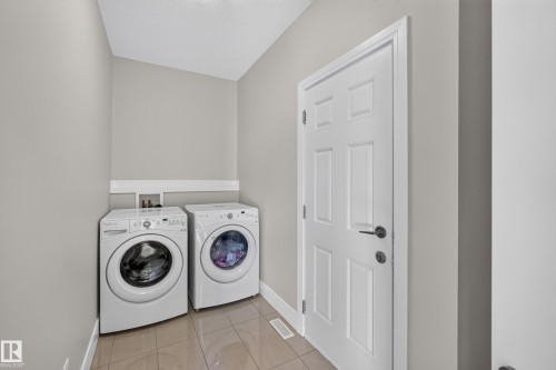 Laundry area featuring a side-by-side washer and dryer, panel door, and tile flooring - 3685 Claxton Place Sw, Edmonton, AB 