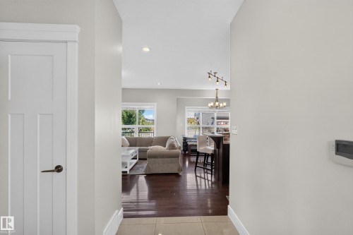 Hardwood flooring throughout the primary living areas, recessed lighting, and a modern chandelier - 3685 Claxton Place Sw, Edmonton, AB 