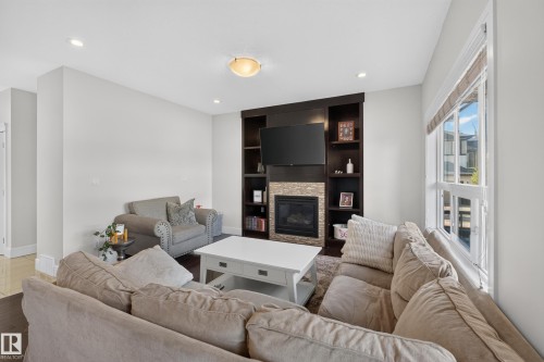 Built-in media center with shelving, recessed lighting, and a stacked stone fireplace - 3685 Claxton Place Sw, Edmonton, AB 