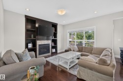 Dark wood-finish flooring, built-in shelving, stone-clad fireplace, recessed lighting, and a large window - 