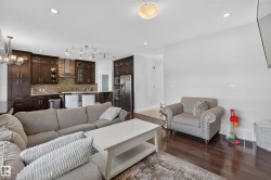 Open-concept living area featuring rich wood-finish flooring, recessed lighting, and a modern kitchen - 