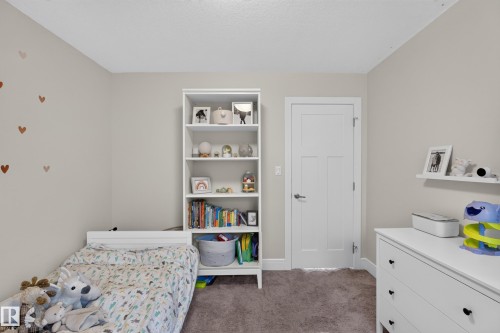 Neutral wall finish, built-in shelving, white paneled door with brushed nickel hardware, and carpeted flooring - 3685 Claxton Place Sw, Edmonton, AB 