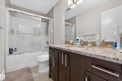 Built-in vanity with a double-basin countertop, undermount sinks, and dark wood-finish cabinetry - 3685 Claxton Place Sw, Edmonton, AB 