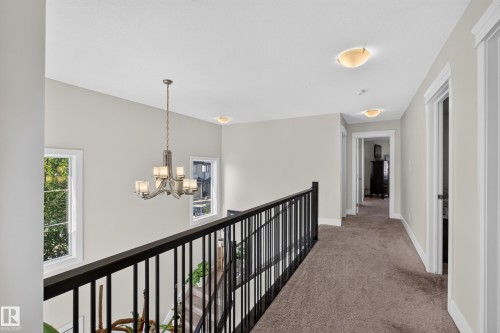 Open landing with a chandelier, dual windows, dark railing, and recessed ceiling lights - 3685 Claxton Place Sw, Edmonton, AB 
