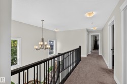 Open landing with a chandelier, dual windows, dark railing, and recessed ceiling lights - 