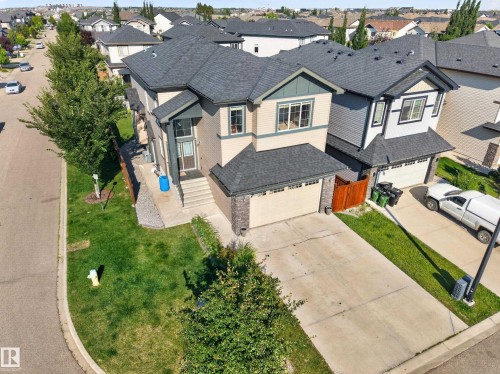 Two-story residence featuring a shingled roof, attached garage with a concrete driveway, and a landscaped front yard with mature trees - 3685 Claxton Place Sw, Edmonton, AB 