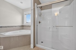 Built-in corner soaking tub with tile surround, mosaic accent tile, and an adjacent glass-enclosed shower with a built-in bench - 