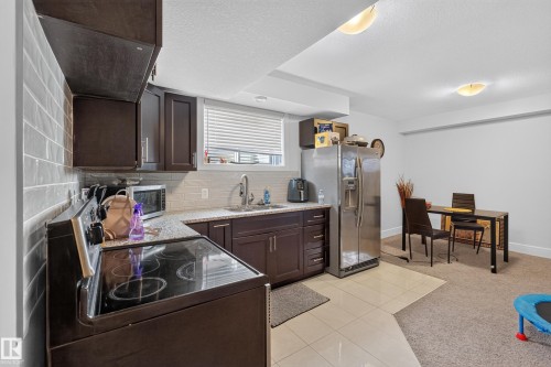 Kitchen area featuring dark wood-finish cabinetry, light-toned countertop, and tile backsplash - 3685 Claxton Place Sw, Edmonton, AB 