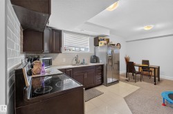 Kitchen area featuring dark wood-finish cabinetry, light-toned countertop, and tile backsplash - 