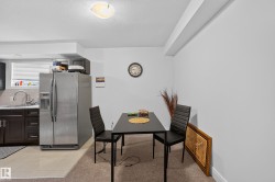 Stainless steel refrigerator, dark wood-finish cabinetry, light tile flooring, and a ceiling-mounted light fixture - 