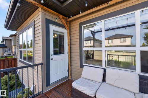 Exterior deck with wood-finish flooring, white paneled door, and metal railing - 3685 Claxton Place Sw, Edmonton, AB 