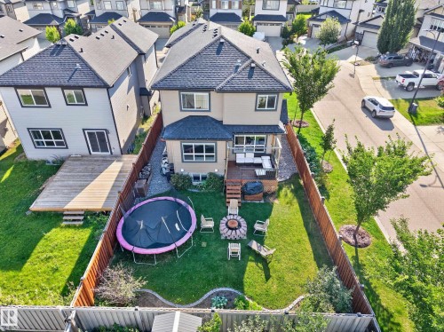 Expansive backyard featuring a manicured lawn, a large deck with railings, and a distinct fire pit area - 3685 Claxton Place Sw, Edmonton, AB 