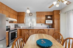 Warm wood cabinetry throughout the kitchen features ample storage and counter space, complemented by stainless steel appliances and a ceramic sink - 