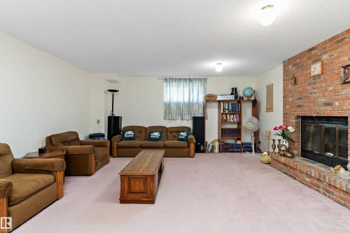 Spacious room featuring a brick-clad fireplace with a hearth, light-colored walls, and a built-in bookshelf - 17724 94 Street Nw, Edmonton, AB 