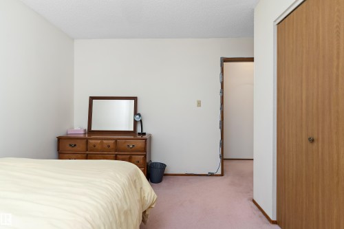 Spacious bedroom featuring hardwood dresser with mirror, generous floor space, and direct access to an ensuite bathroom - 17724 94 Street Nw, Edmonton, AB 