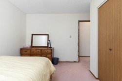 Spacious bedroom featuring hardwood dresser with mirror, generous floor space, and direct access to an ensuite bathroom - 