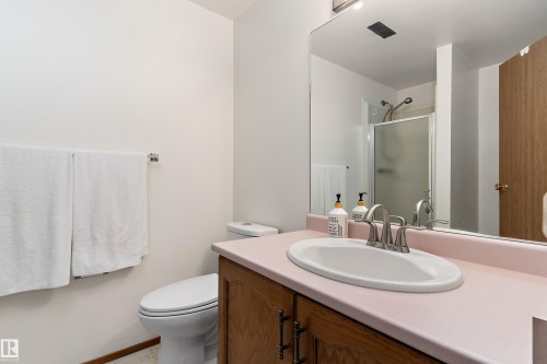 Vanity with an integrated oval sink, brushed nickel faucet, and wood-finish cabinetry - 17724 94 Street Nw, Edmonton, AB 