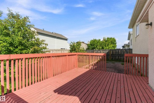 Expansive wood deck with a red finish, featuring a full railing system, and a brick patio area - 17724 94 Street Nw, Edmonton, AB 