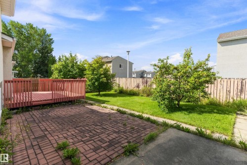Expansive backyard featuring a wood deck, brick patio, and grass lawn with mature trees - 17724 94 Street Nw, Edmonton, AB 