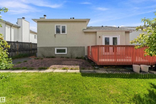 Spacious backyard featuring a manicured lawn, mature landscaping, and a composite deck with metal railings - 17724 94 Street Nw, Edmonton, AB 