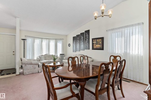 Elegant dining room showcasing a round wood-finish table with seating for six, paired with Queen Anne-style chairs - 17724 94 Street Nw, Edmonton, AB 