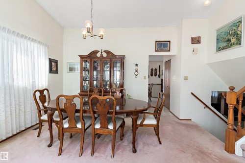 Elegant dining room showcasing a wood pedestal table, Queen Anne-style chairs, and a traditional china cabinet with glass doors - 17724 94 Street Nw, Edmonton, AB 