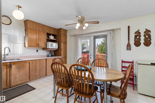 Warm wood cabinetry and stainless steel fixtures define this eat-in kitchen, featuring ample counter space and storage - 17724 94 Street Nw, Edmonton, AB 