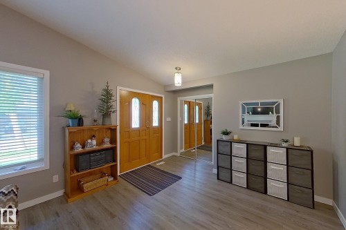 Spacious entry hall featuring light wood-finish flooring, a vaulted ceiling, and double entry doors with decorative glass inserts - 16 Brunswick Crescent, St. Albert, AB - Indoor