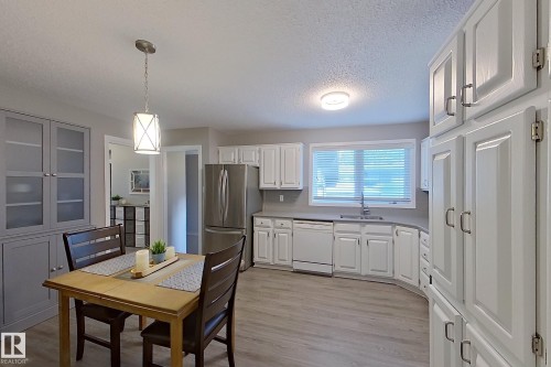 Bright kitchen featuring white cabinetry, stainless steel refrigerator, and wood-finish flooring - 16 Brunswick Crescent, St. Albert, AB - Indoor