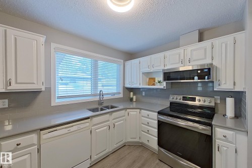 Kitchen featuring white cabinetry, grey subway tile backsplash, light grey countertops, stainless steel appliances, and wood-finish flooring - 16 Brunswick Crescent, St. Albert, AB - Indoor Photo Showing Kitchen With Double Sink