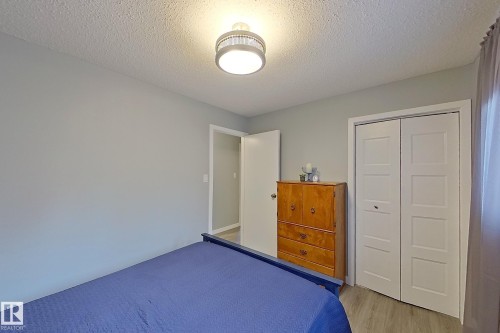 Light gray wall paint, wood-finish flooring, white bi-fold closet doors, and an overhead flush-mount light fixture - 16 Brunswick Crescent, St. Albert, AB - Indoor Photo Showing Bedroom