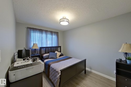 Bedroom featuring light grey wall paint, wood-finish flooring, a window with sheer curtains, a semi-flush mount ceiling light, and white baseboards - 16 Brunswick Crescent, St. Albert, AB - Indoor Photo Showing Bedroom
