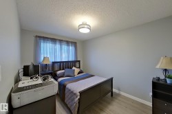 Bedroom featuring light grey wall paint, wood-finish flooring, a window with sheer curtains, a semi-flush mount ceiling light, and white baseboards - 