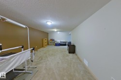 Spacious lower-level room featuring plush carpet flooring, recessed lighting, and a textured ceiling - 